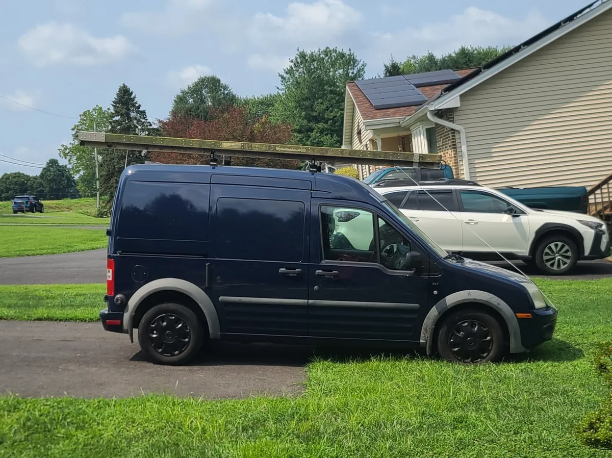 Dark blue Birds Beware Ford Transit Connect work van with ladder